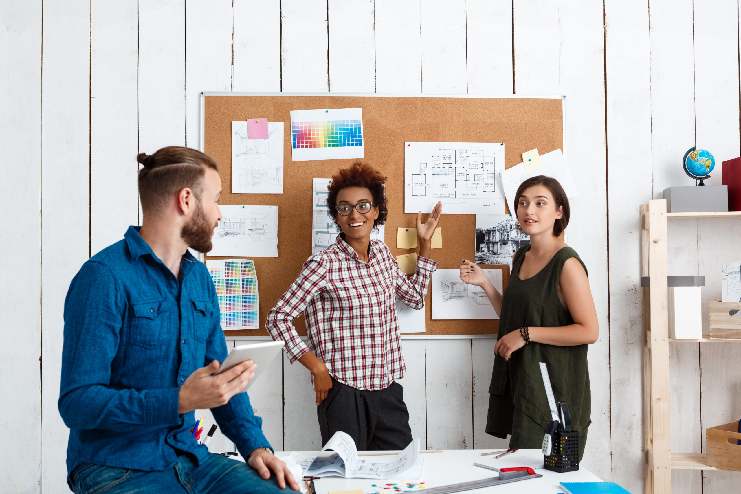 Colleagues smiling, speaking, discussing drawings, new ideas in office